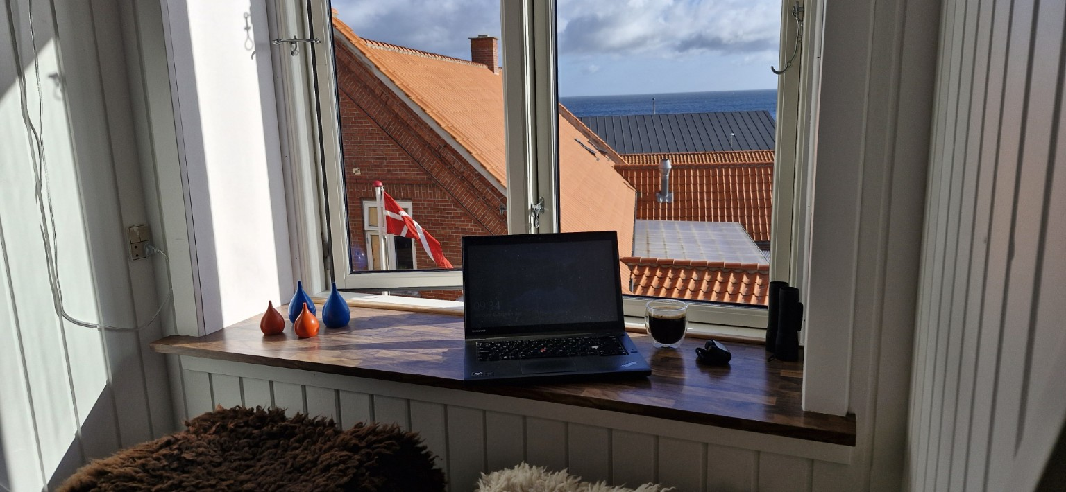 Bærbar computer, mobiltelefon og kaffe ved vinduet i Allinge