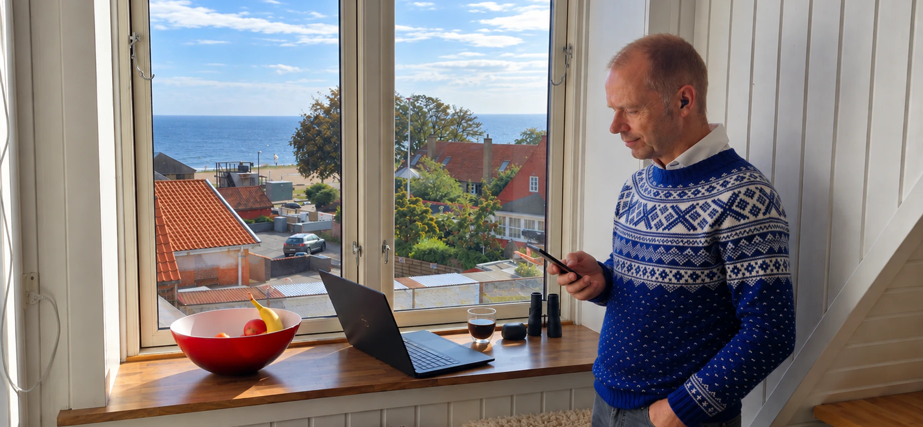 David Hav i telefonsamtale med Jabra earbud ved vinduet i Allinge